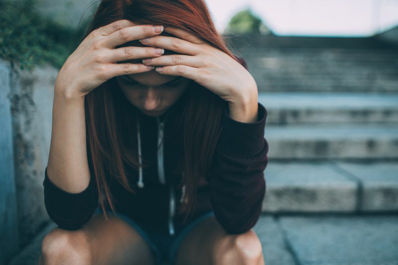 Depressed woman sitting on a staircase outdoors.